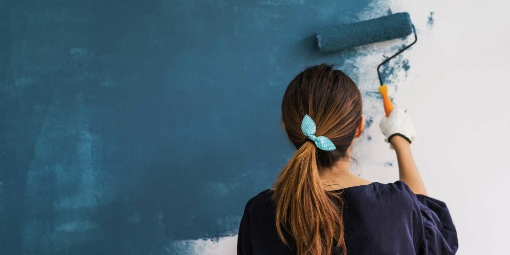 Women is DIY painting her wall with fresh colour